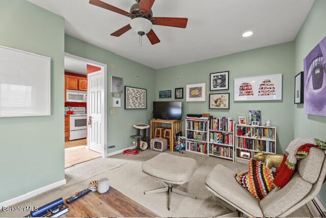 living area with carpet flooring, a ceiling fan, and baseboards