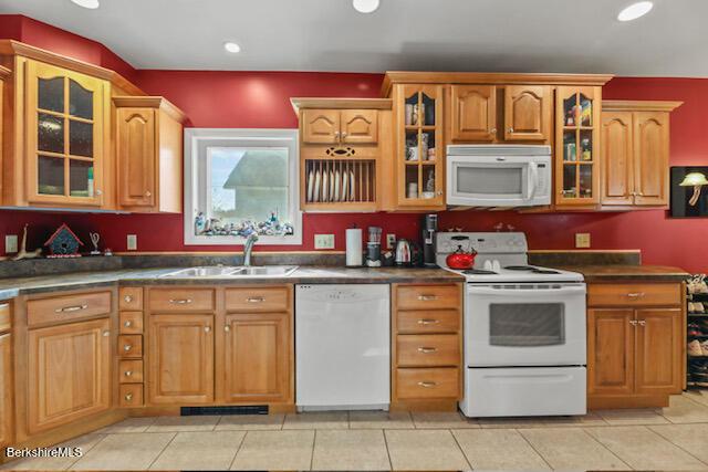 kitchen featuring white appliances, dark countertops, and a sink