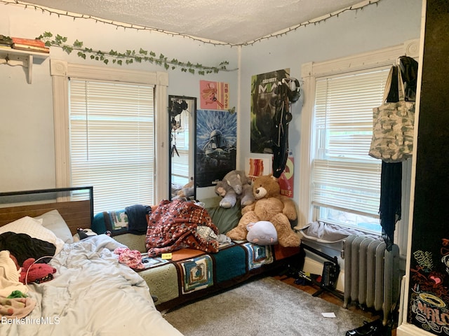 bedroom with radiator heating unit and a textured ceiling