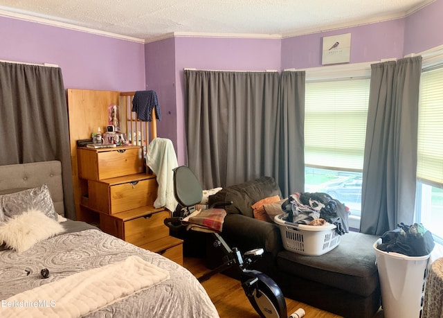 bedroom with wood-type flooring, ornamental molding, and a textured ceiling