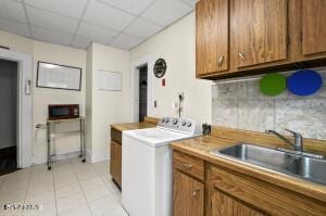 washroom featuring washer / clothes dryer, light tile patterned floors, and cabinet space