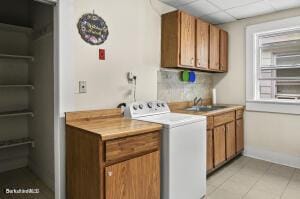 washroom with washer / dryer, light tile patterned flooring, and cabinet space