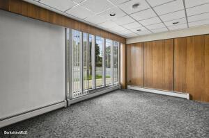 spare room featuring a baseboard radiator, a drop ceiling, and wooden walls