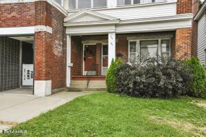 view of exterior entry with brick siding and a lawn