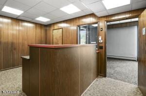 reception featuring a paneled ceiling, a bar, and wood walls