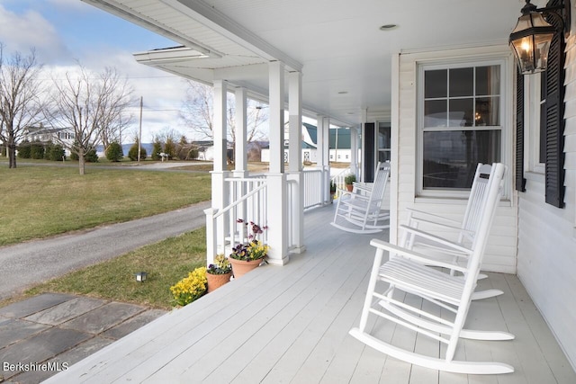 wooden terrace featuring a lawn and covered porch