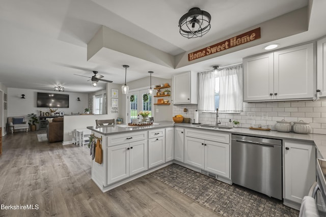 679 Middle Pownal Rd, Pownal, VT 05261 - kitchen featuring stainless steel dishwasher, a peninsula, backsplash, wood finished floors, and white cabinetry