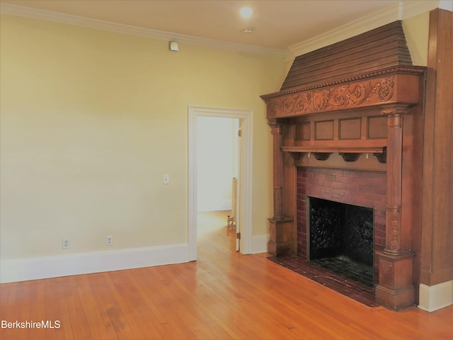 unfurnished living room with a fireplace, wood-type flooring, crown molding, and baseboards