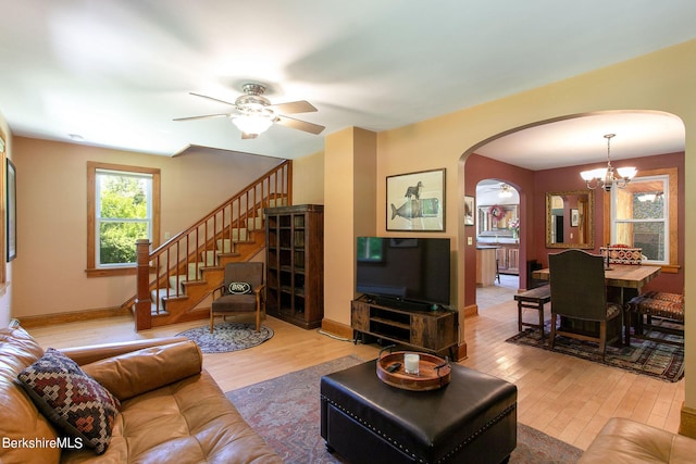 living room with ceiling fan with notable chandelier and light wood-type flooring