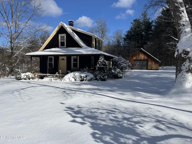 farmhouse featuring an outbuilding, a garage, and a front lawn