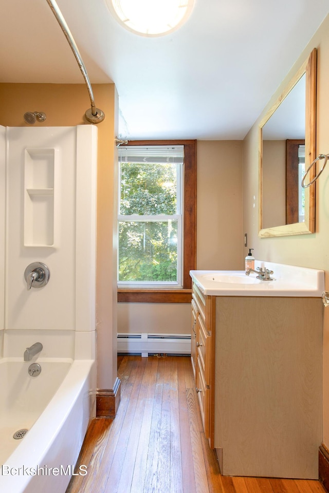 bathroom with bathing tub / shower combination, vanity, hardwood / wood-style flooring, and baseboard heating