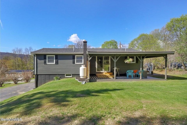 back of property with a lawn and a chimney