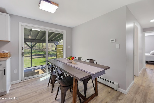 dining room featuring baseboards, a baseboard radiator, and light wood finished floors