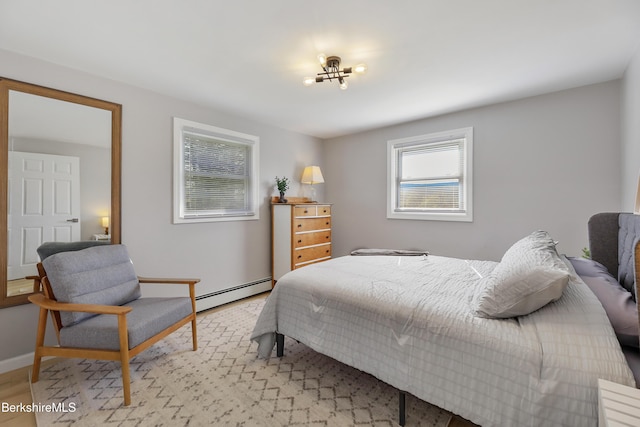 bedroom featuring baseboards, light wood finished floors, and a baseboard radiator