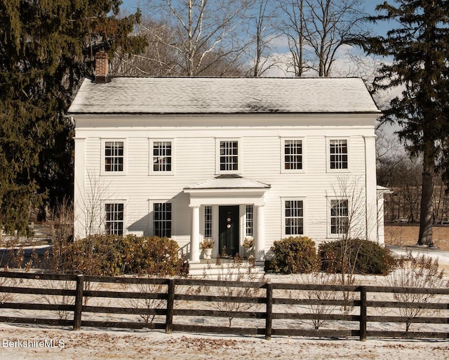 colonial home featuring a fenced front yard and a chimney