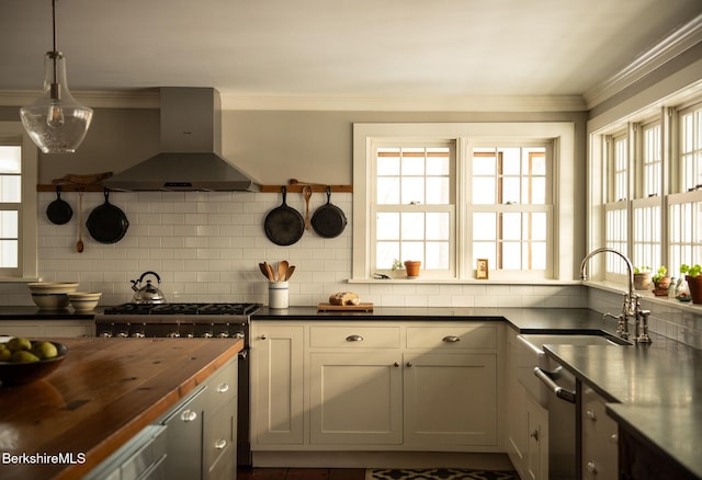 kitchen featuring a sink, wood counters, wall chimney exhaust hood, tasteful backsplash, and crown molding