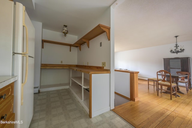kitchen featuring open shelves, light floors, a baseboard radiator, and freestanding refrigerator