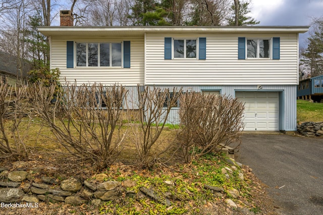view of front of property with an attached garage, driveway, and a chimney