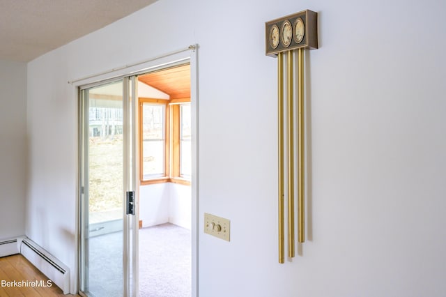 doorway to outside with baseboard heating and wood finished floors