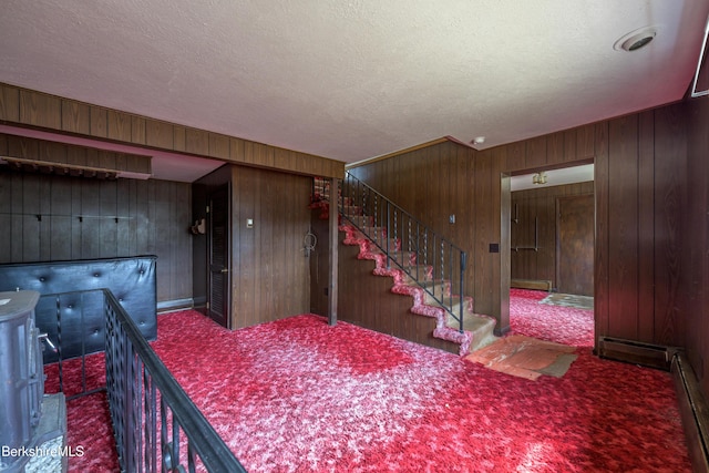 staircase with wooden walls, carpet floors, and a textured ceiling