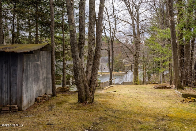 view of yard with an outdoor structure, a water view, and a shed