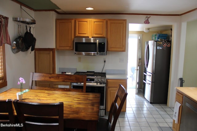 kitchen with ornamental molding, appliances with stainless steel finishes, and light tile patterned floors