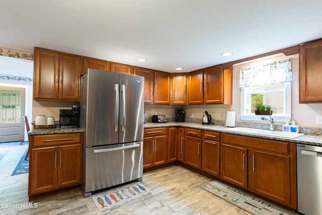 144 Brombach St, Pittsfield, MA 01201 - kitchen with appliances with stainless steel finishes, a sink, brown cabinets, light stone countertops, and light wood-type flooring