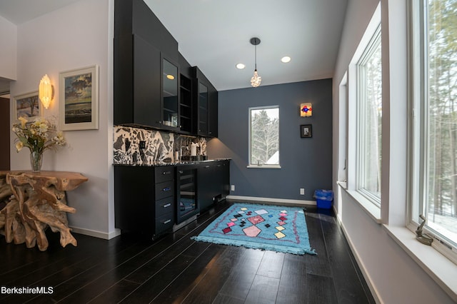 bar with wine cooler, dark wood-style flooring, backsplash, and baseboards