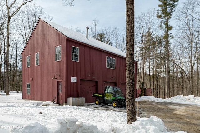 snow covered house featuring an attached garage and a shingled roof