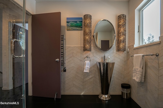 bathroom with a shower with door and tile walls