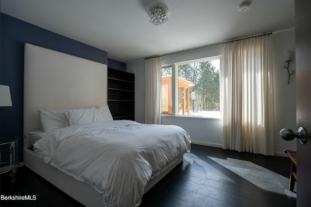 bedroom with baseboards and dark wood-type flooring