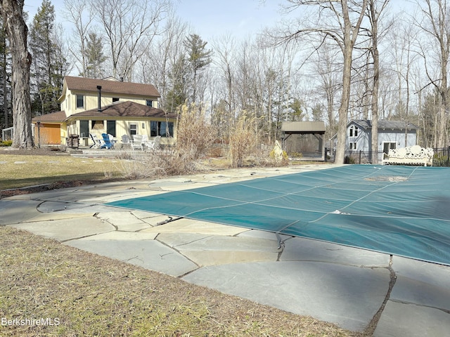 view of swimming pool with a covered pool, a patio, and fence