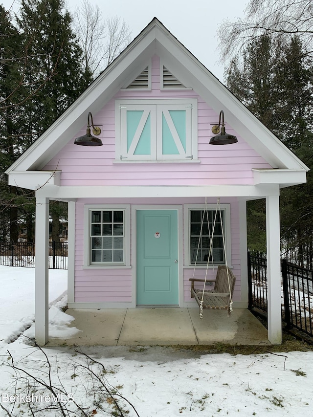 view of outdoor structure with covered porch and fence