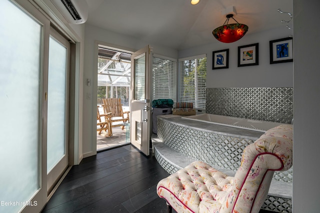 interior space with a wall mounted AC, wood-type flooring, and a garden tub