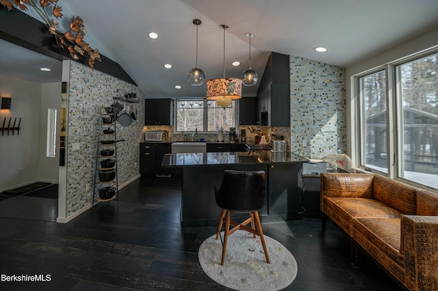 kitchen with lofted ceiling, dark cabinets, a peninsula, and dark wood-type flooring