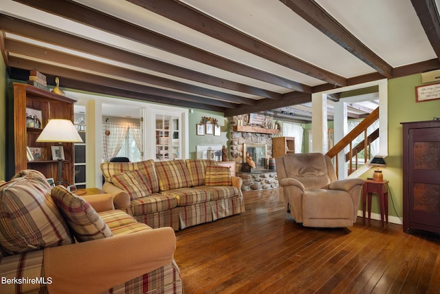 living room featuring beamed ceiling, dark hardwood / wood-style flooring, and a stone fireplace