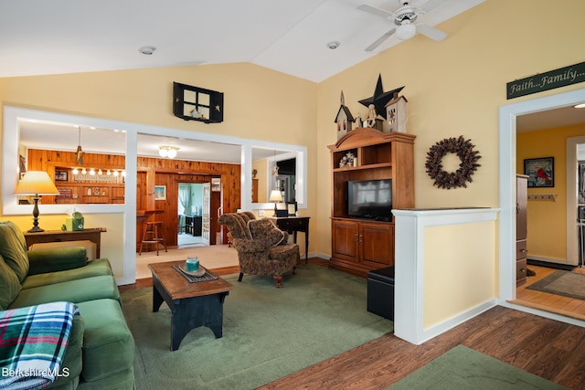 living room featuring wood walls, vaulted ceiling, ceiling fan, built in shelves, and wood-type flooring