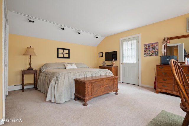 carpeted bedroom with rail lighting and lofted ceiling