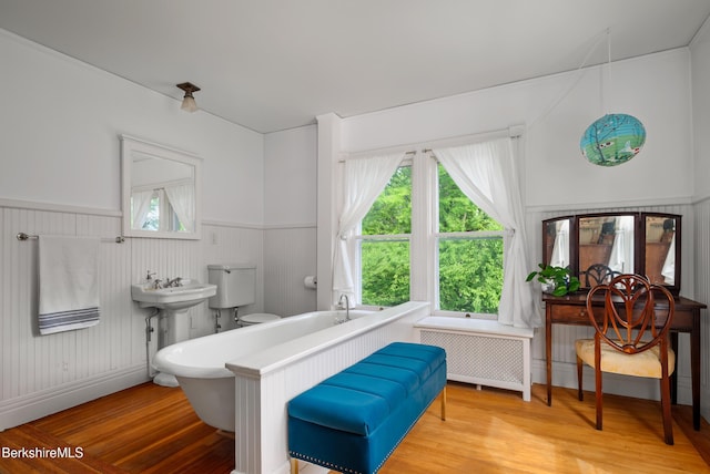 163 Cole Ave, Williamstown, MA 01267 - bathroom with radiator, wood finished floors, a wainscoted wall, and a tub to relax in