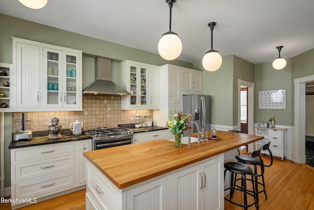 163 Cole Ave, Williamstown, MA 01267 - kitchen with wall chimney exhaust hood, appliances with stainless steel finishes, butcher block counters, tasteful backsplash, and white cabinetry