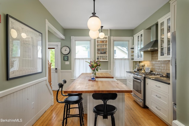 163 Cole Ave, Williamstown, MA 01267 - kitchen featuring gas range, butcher block countertops, wall chimney range hood, wainscoting, and white cabinets