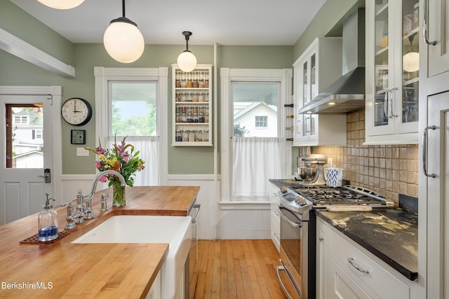 163 Cole Ave, Williamstown, MA 01267 - kitchen with appliances with stainless steel finishes, butcher block countertops, wall chimney range hood, light wood finished floors, and a wainscoted wall