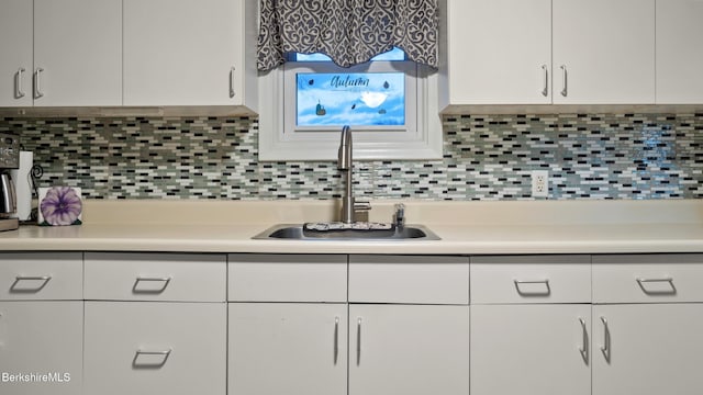 kitchen with tasteful backsplash, sink, and white cabinets