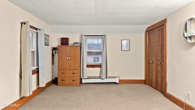 carpeted bedroom featuring a baseboard radiator, vaulted ceiling, and a closet