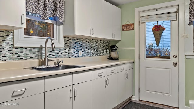 kitchen with tasteful backsplash, sink, and white cabinets