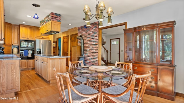 dining room featuring an inviting chandelier, a wood stove, sink, and light hardwood / wood-style flooring