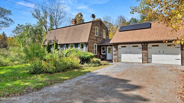 view of front facade featuring solar panels, a garage, and a front yard