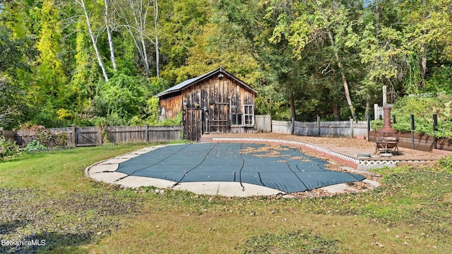 view of swimming pool featuring a yard and an outdoor fire pit