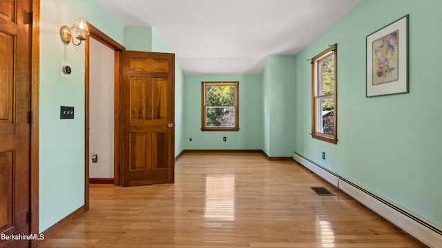 unfurnished room with light wood-type flooring and a baseboard heating unit