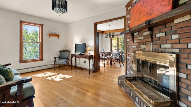 sitting room featuring a healthy amount of sunlight, light hardwood / wood-style floors, a baseboard radiator, and an inviting chandelier